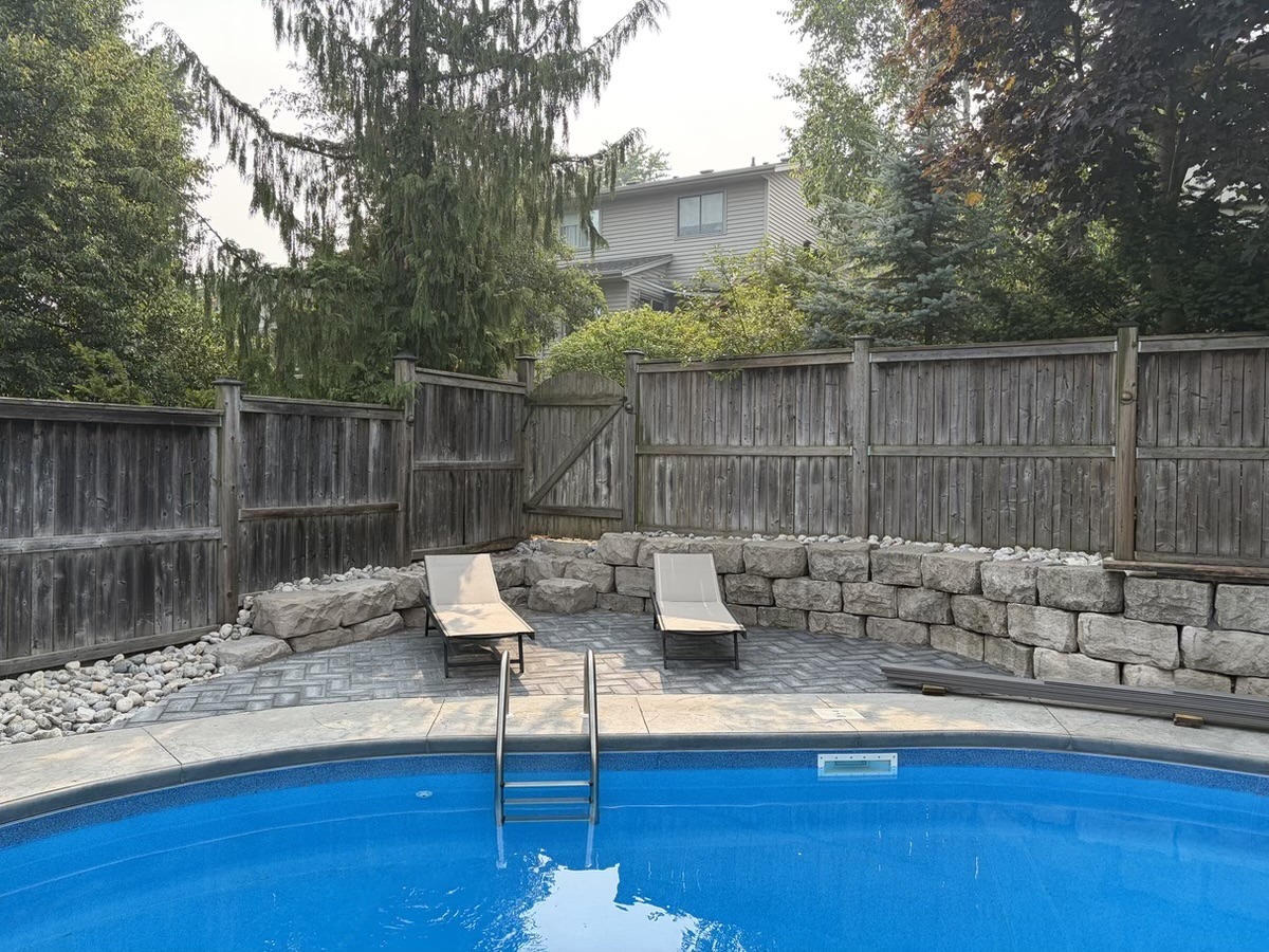 Pool patio framed by a retaining wall and stone work by Brothers Landscaping