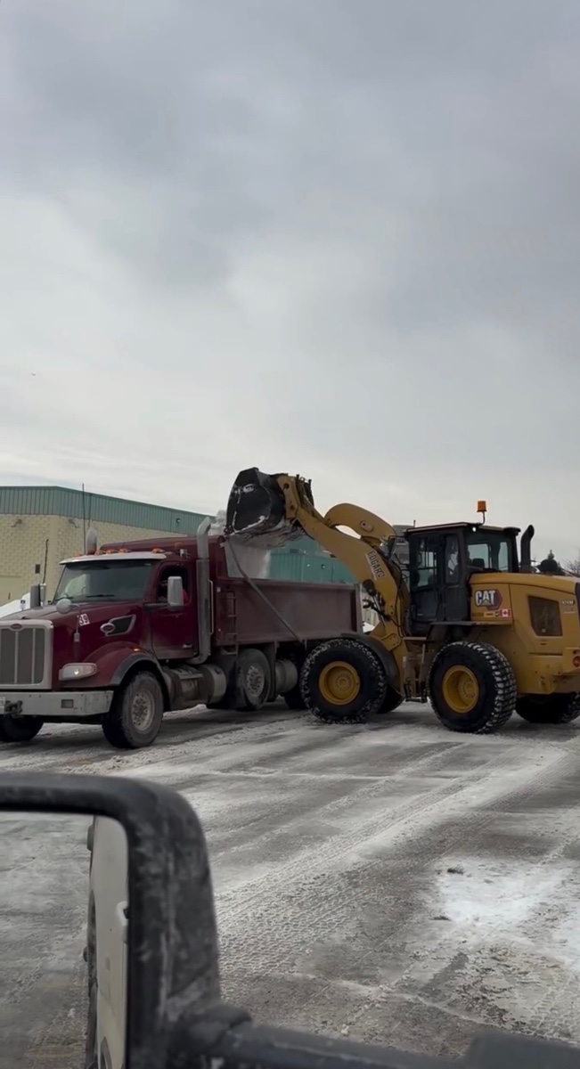 Loader and dump truck working together in a commercial lot