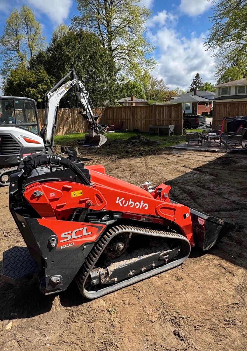 Skid steer and excavator working together on a backyard grading project
